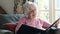 Senior Woman In Armchair At Home Looking At Photo Album