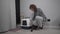 Senior woman assembles new cat litter box together with pet at home. Elderly female playing with cat sets hooded litter