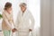 Senior woman in bathrobe with walker and helpful nurse supporting her