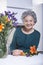 Senior Woman Beside Bouquet of Flowers in the Kitchen, Portrait