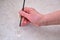 A senior woman with a brush is painting tiles on the kitchen floor. Painting to restore the damaged floor surface