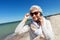 Senior woman calling on smartphone on beach