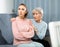 Senior woman calming chagrined adult daughter in home living room
