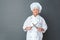 Senior woman chef studio standing isolated on gray sharpening knives looking camera cheerful