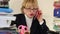 Senior woman chief accountant in glasses and with red smartphone