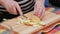 senior woman cut red apple with a knife on wooden cutting board on a kitchen table