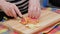 senior woman cut red apple with a knife on wooden cutting board on a kitchen table for apple pie