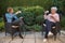 Senior woman and daughter having coffee at safety distance in the garden,