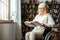 Senior woman with disability recovery at home wheelchair reading book