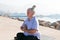 Senior woman with dreadlocks in stretching position by the sea at morning. Elderly woman doing yoga near beach.