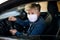 Senior woman driver with face mask in car, quarantine concept.