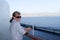 A senior woman enjoys the view from a ship cruising through the straits of Messina, Italy