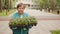 Senior woman gardener holding in hands flower seedling in summer park. Elderly woman walking with flower seedling to