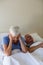 Senior woman getting disturbed with man snoring on bed