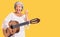 Senior woman with gray hair playing classical guitar screaming proud, celebrating victory and success very excited with raised