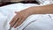 Senior woman hand on bed linen, lying in sick bed, suffering illness, death risk