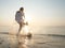 Senior woman having fun splashing water and playing with a ball in sun glare