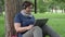 Senior woman having on-line call while sitting on the grass in city park. Education concept.