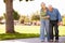 Senior Woman Helping Husband As They Walk In Park Together