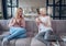 Senior woman and her attractive daughter spending time together at home. Sitting on sofa and drinking tea together. Happy Mothers