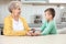 Senior woman with her grandson using digital glucometer at home