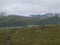 Senior woman hiker at Kungsleden hiking trail with Lapland nature with green mountains, Teusajaure lake, rock boulders, autumn