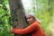 Senior woman hugging a tree, eyes closed