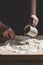 Senior woman kneads pastry, pours water from cup to flour