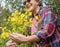 Senior woman laughing hugs a group of yellow flowers in full bloom in the woods