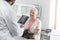 Senior woman looking at doctor standing with digital tablet in veterinary clinic