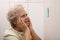 Senior woman looking at reminder note indoors. Age-related memory impairment