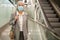 Senior woman in mask beside escalator in mall