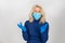 Senior woman in a medical mask and gloves is on a gray background. Attributes of protecting people during a pandemic