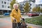 Senior woman with a mobility walker walking on city streets during autumn day, enjoying the beautiful sunny weather