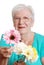 Senior woman offering a fake daisy focus on flower