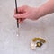 A senior woman paints an ornament with a brush on a damaged floor tile. Paint for the reconstruction of the floor surface in the