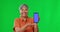 Senior woman, phone and mockup on green screen with tracking markers against a studio background. Portrait of happy