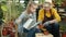 Senior woman planting flowers while granddaughter helping her in glasshouse