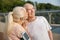 Senior woman with ponytail kisses happy husband at training on footbridge