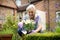 Senior Woman Potting Plant In Garden At Home