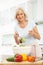 Senior Woman Preparing Salad In Modern Kitchen