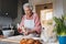 Senior woman preparing traditional easter meals for family, kneading dough for easter cross buns. Recreating family