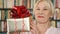 Senior woman with present. Pensioner holding golden gift box with red ribbon celebrating birthday