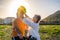 Senior woman puts protective helmet on her husband to ride a bicycle. Bright sunset light