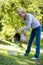 Senior woman putting potatoes in bowl from bucket in garden