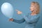 Senior woman r holding a blue balloon being alone on her Birthday party