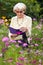 Senior woman reading amongst summer flowers