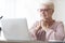 Senior woman reading article online, using laptop