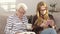 Senior woman reading a book and young woman using a smartphone while drinking a tea. Family bonding