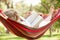 Senior Woman Relaxing In Hammock With Book